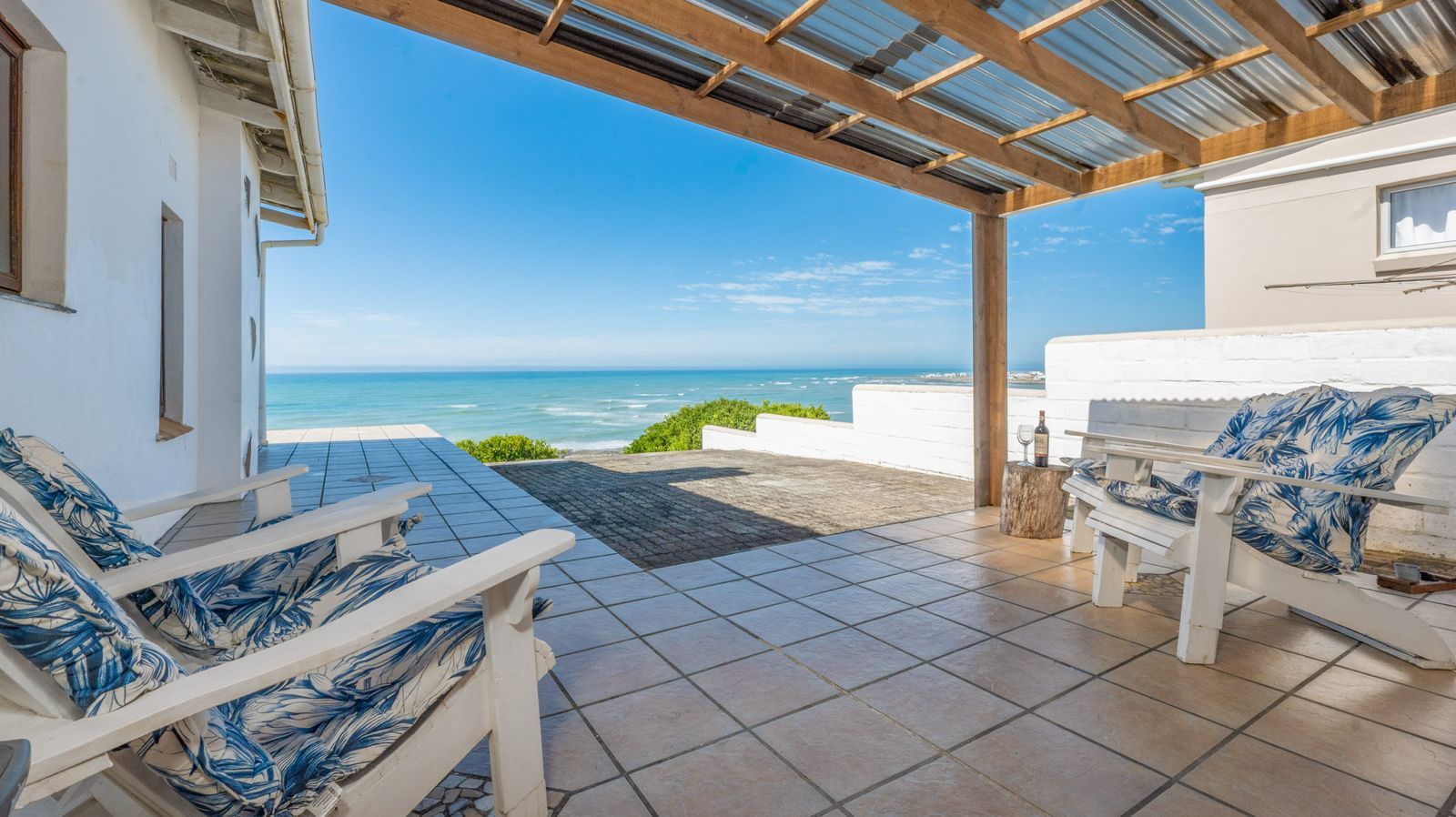 Covered patio with Adirondack chairs and a view of the sea at Whale Watchers, Struisbaai